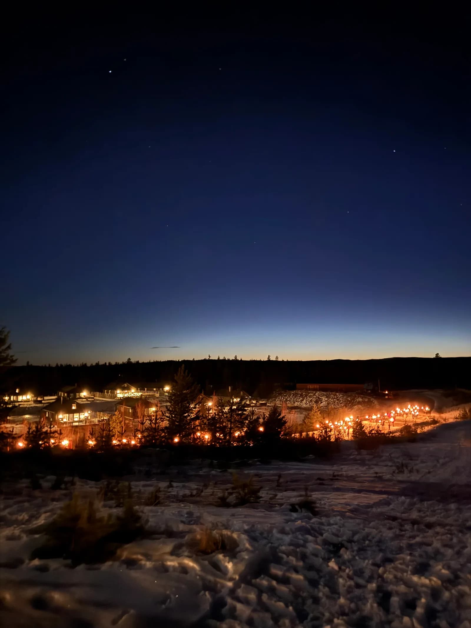 En lang rekke fakler lyser opp snøen ved Furutangen i skumringen.